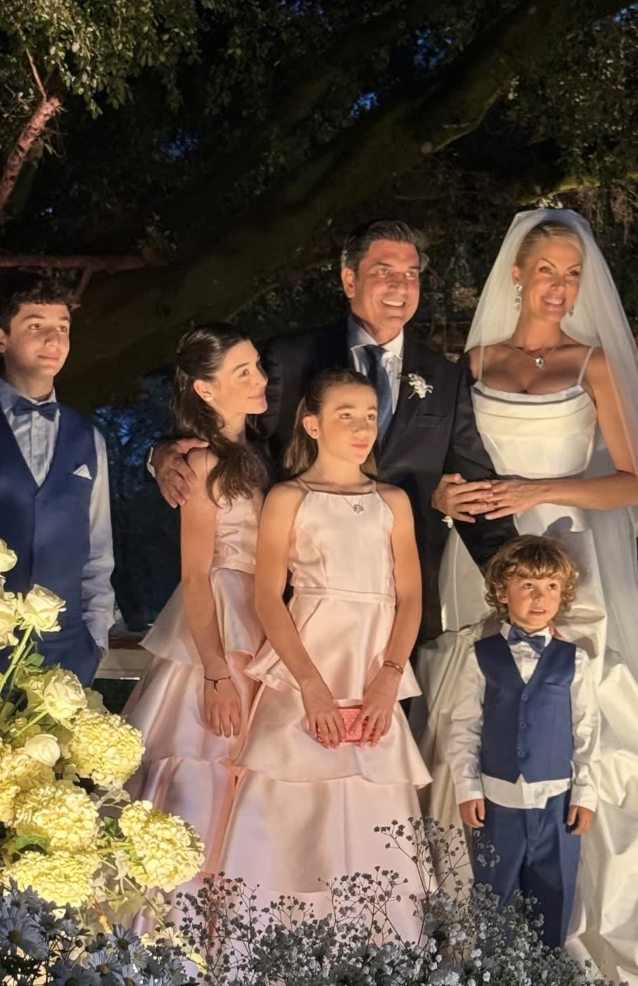 Os noivos com a família no jardim iluminado, durante a festa à noite