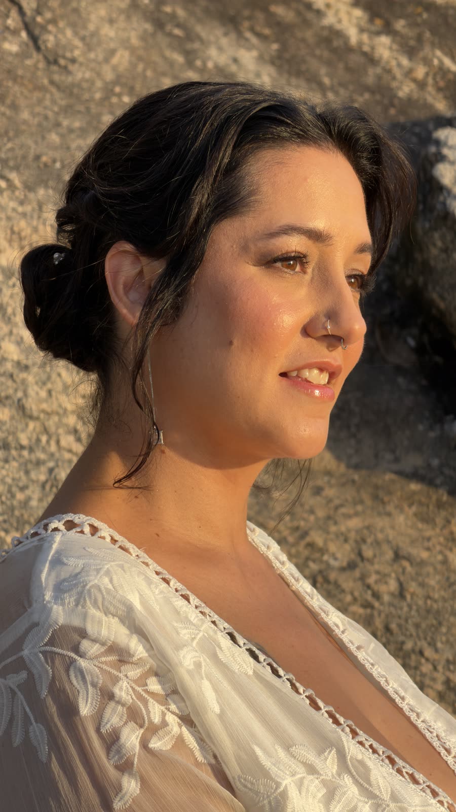 Perfil da noiva ao sol baixo, cabelo preso com fios soltos e pele iluminada