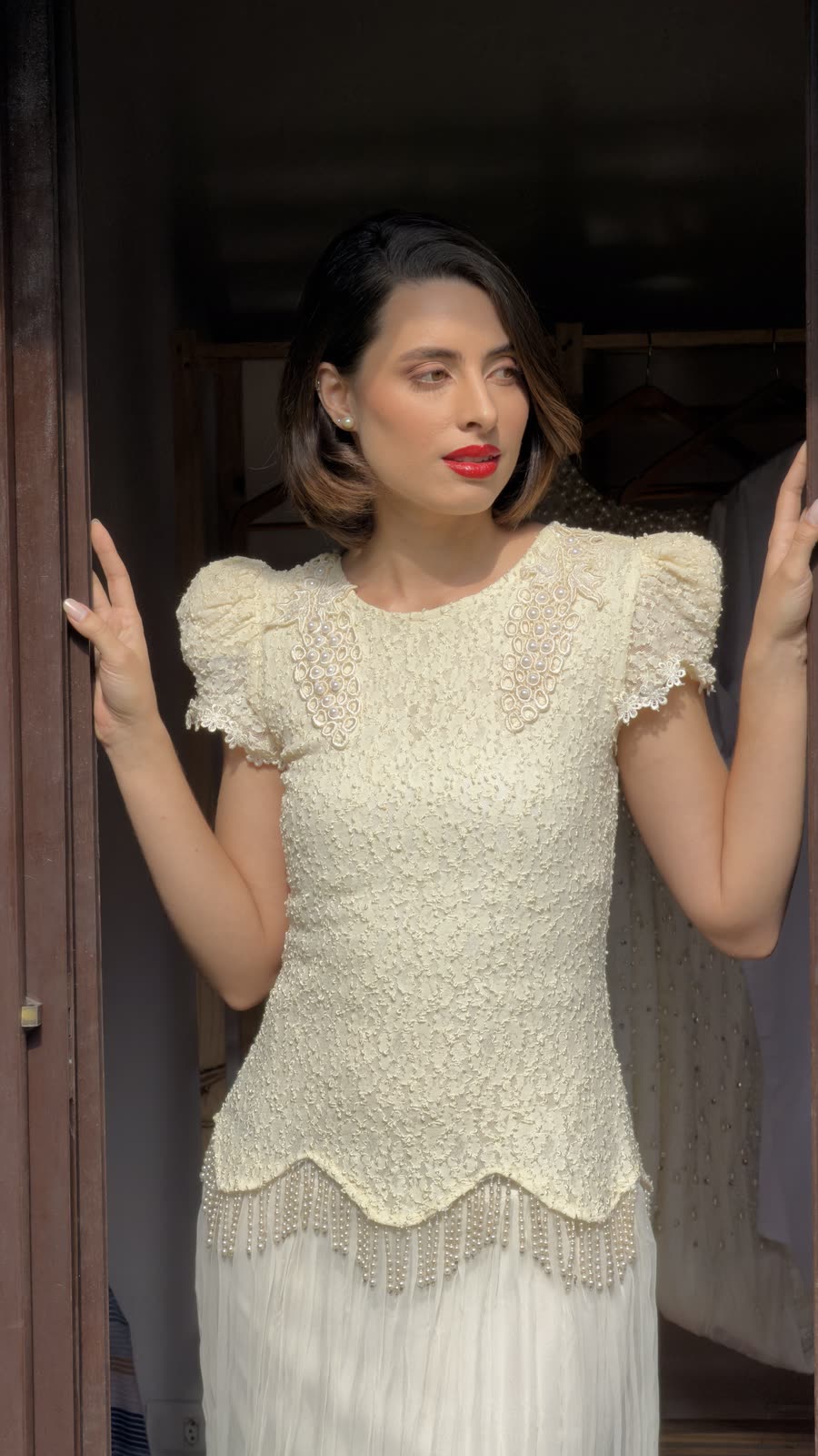 Noiva em pé na porta de madeira, vestido de renda com saia plissada